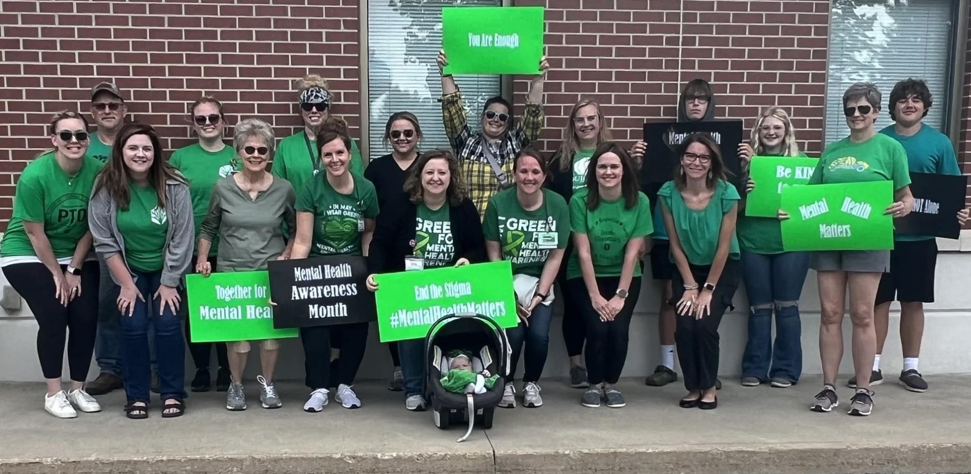 Mitchell County Public Health team members wearing green and holding mental health awareness signage in support of mental health.
